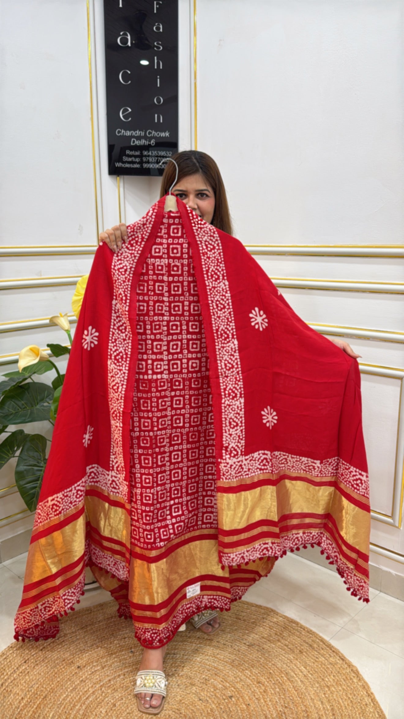 Model showcasing a vibrant red premium batik suit with intricate patterns and golden accents